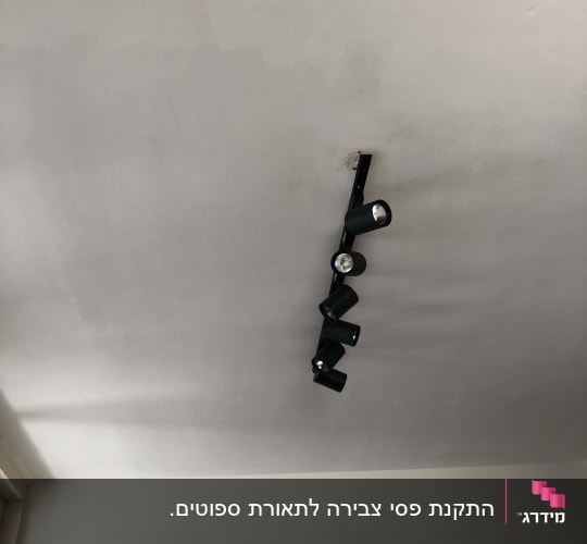 תאורת מסילה עם ארבעה פנסים על תקרה לבנה